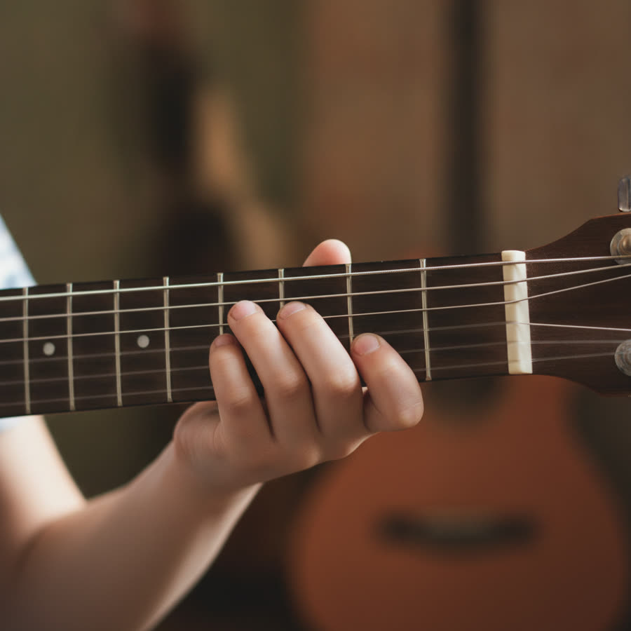 A pre-teen pressing guitar strings — precise finger work